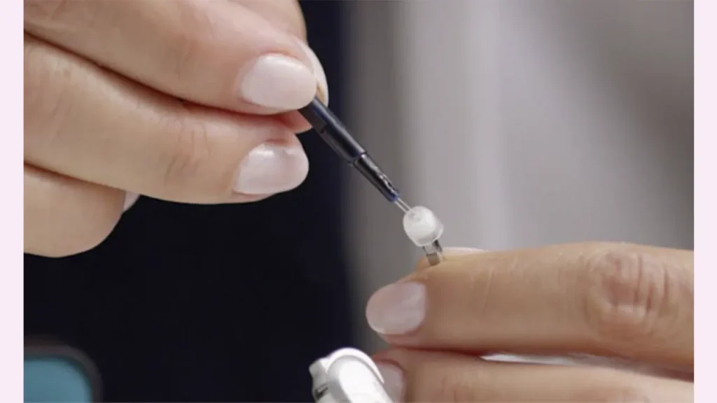 یک خانم در حال تعویض فیلتر سمعک